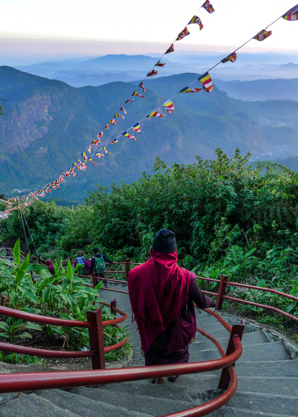 Home monk in red robes descends staircase on adams peak